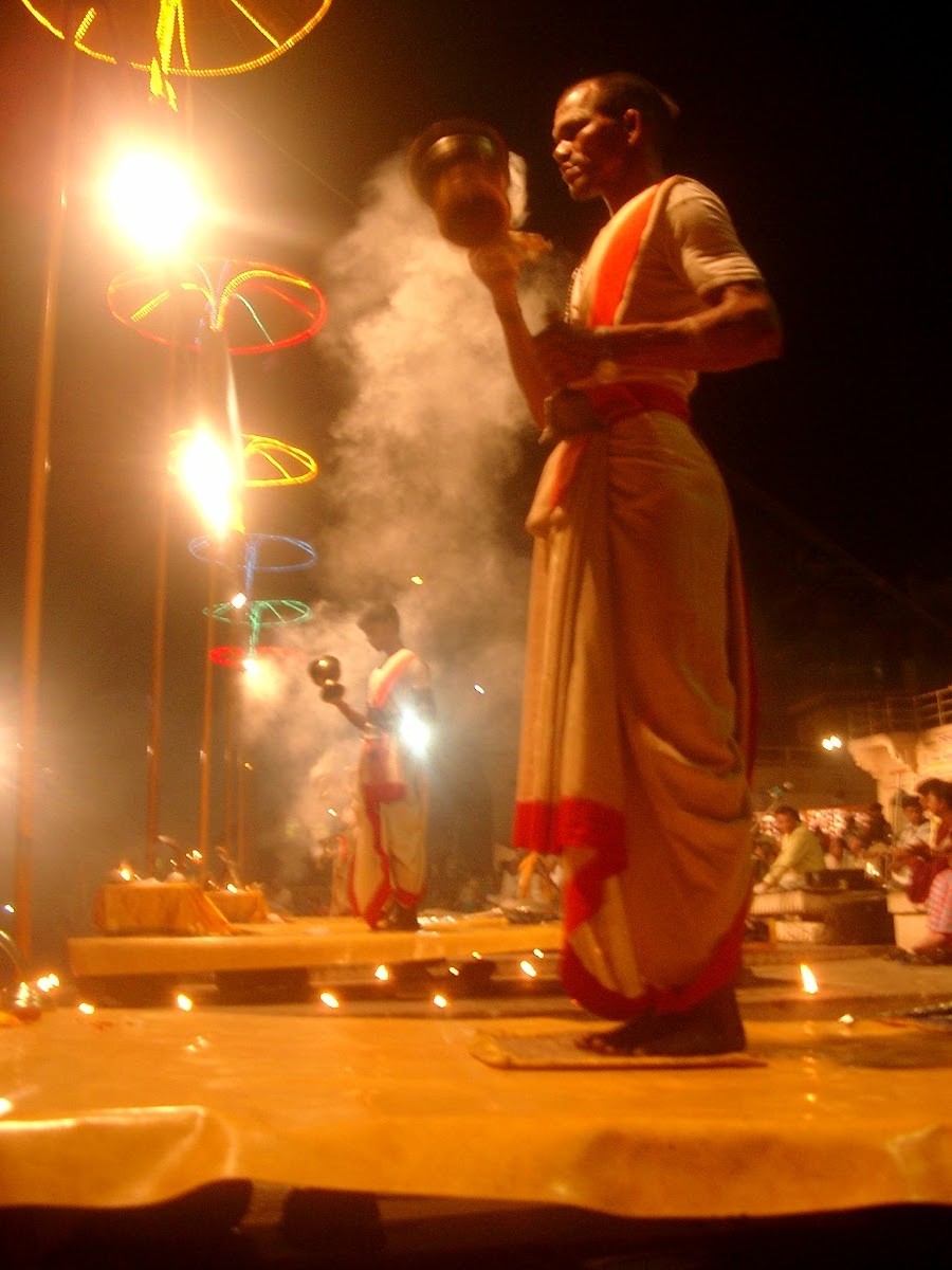 Een priester zwaait met een vuurlamp tijdens de avondceremonie aan de Ganges