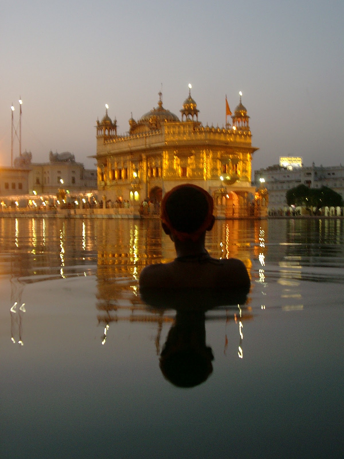 De Gouden Tempel van Amritsar in de schemering, weerspiegeld in het heilige meer