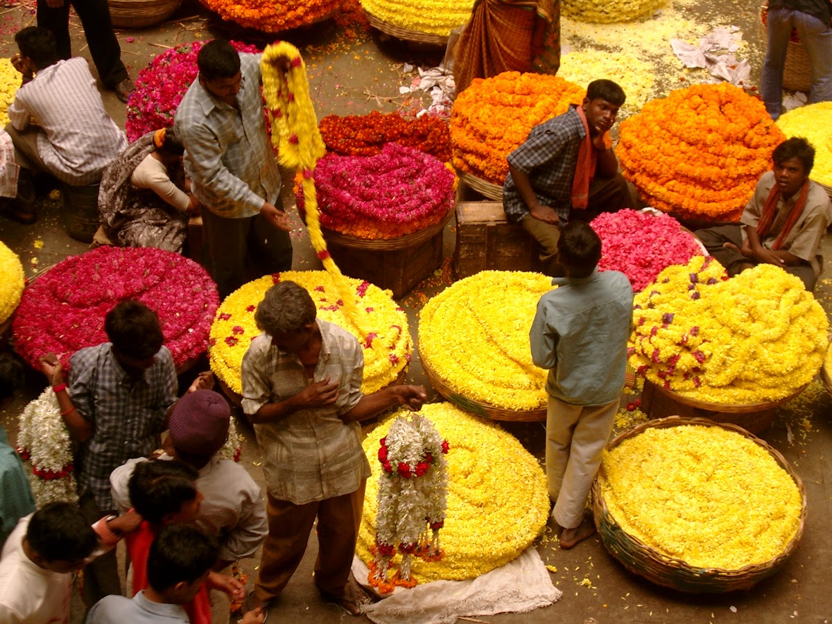 Manden vol gele en rode bloemenkransen op de markt van Mysore