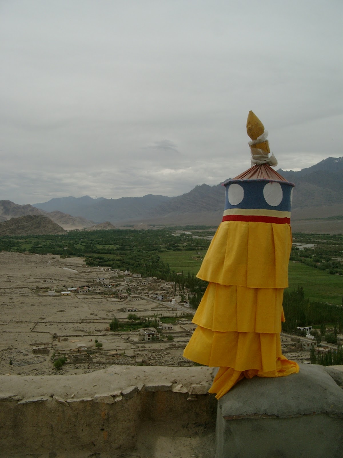 Een met geel doek omwikkelde stoepa boven de vallei van de Indus bij Tiksay