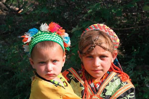 Twee Kalash-meisjes met kleurrijke traditionele hoofdtooien